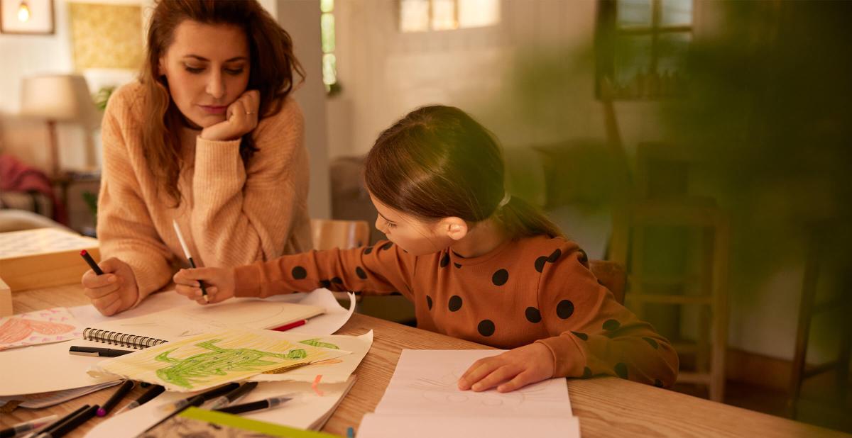Merkur Versicherung – Frau und Kind sitzen am Tisch und machen Hausaufgaben